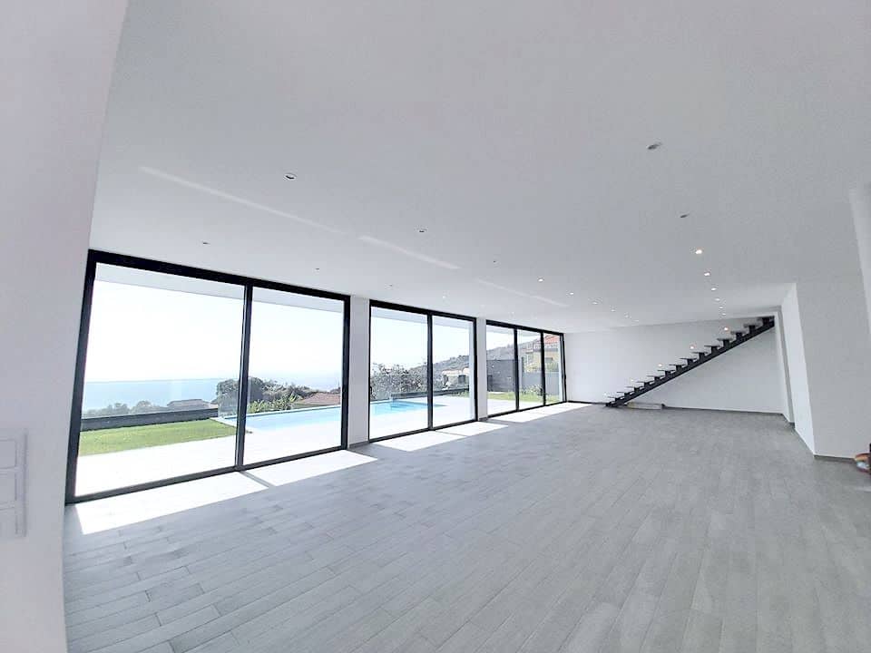 Großer leerer Wohnbereich mit Glasfront und Poolblick