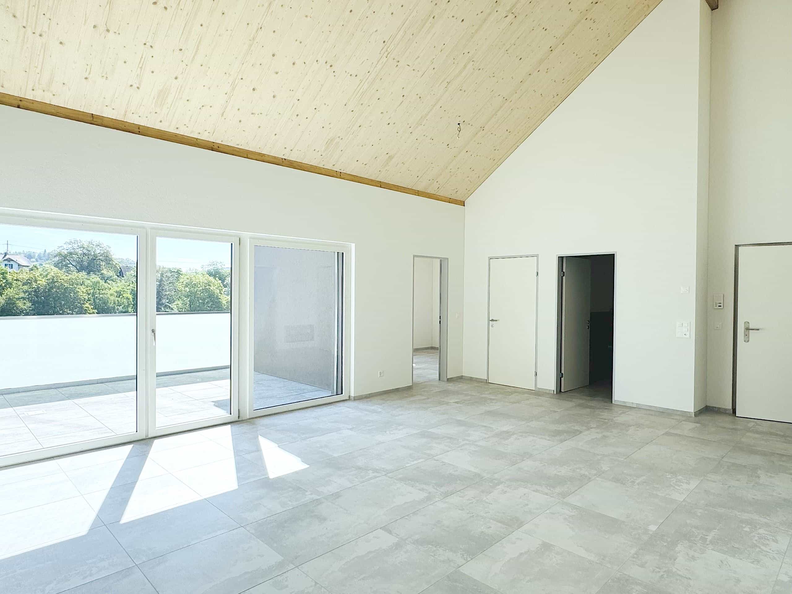 Großer leerer Wohnraum mit Dachschräge und Terrasse